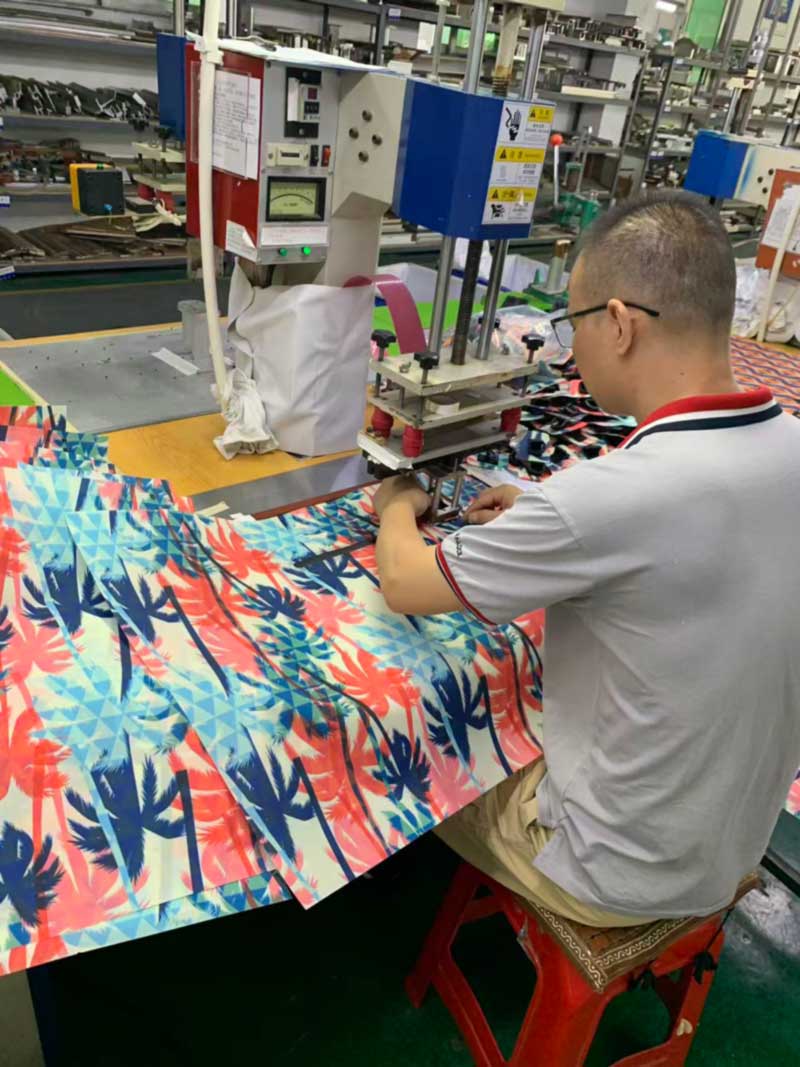 Operator welding a seam on large-scale printed coated fabric at a high-frequency station